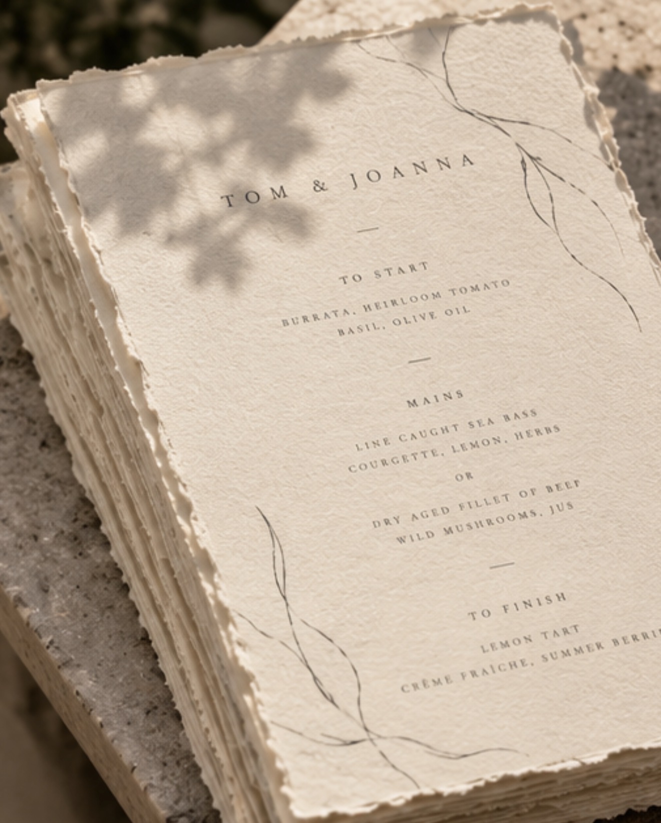 Stack of handmade paper menus with deckled edges and botanical illustrations